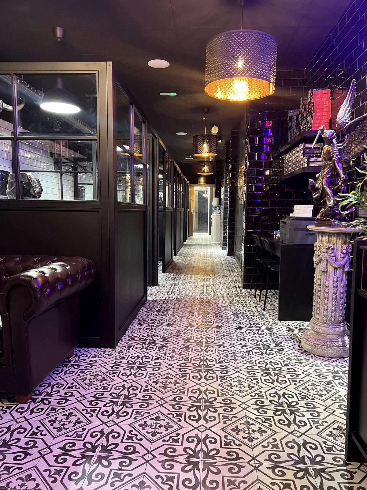 Pasillo de cabinas de un estudio Calipso con suelo hidráulico, vitrinas negras y sillón Chesterfield de cuero.